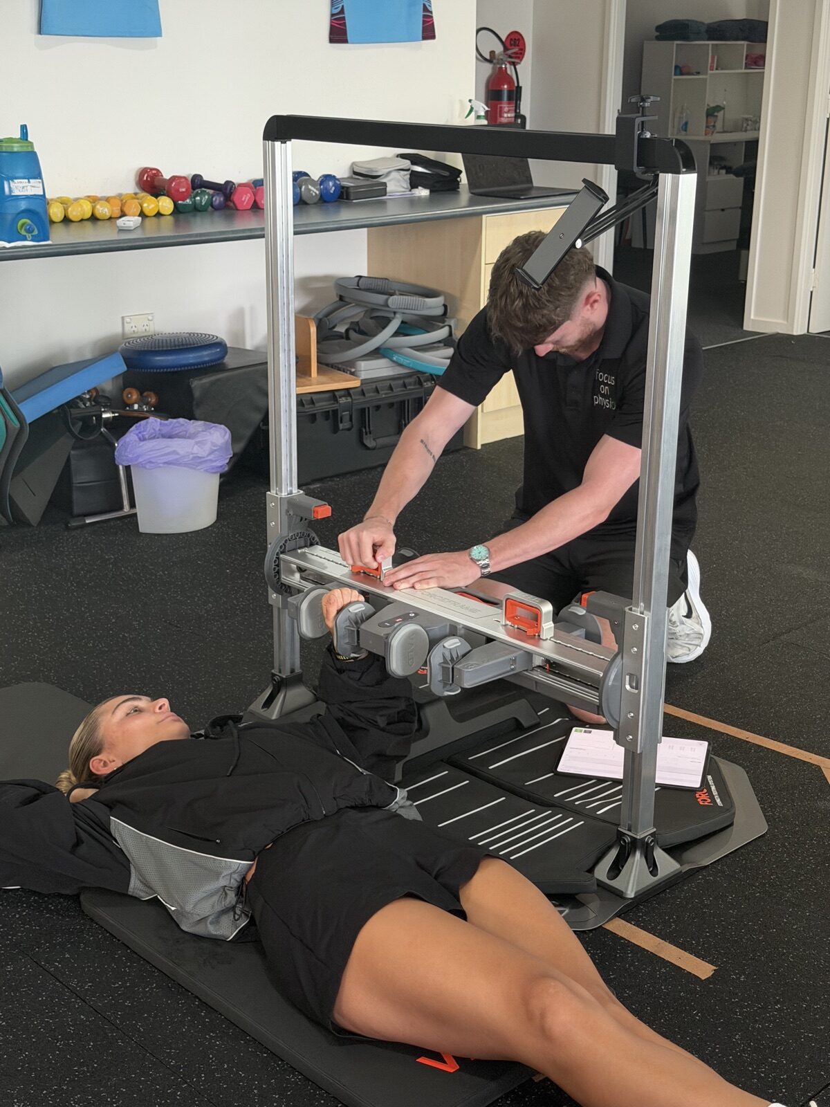 Physio reading strength test results on a tablet during a ForceFrame test